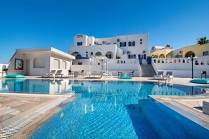 Une piscine d’un bleu éclatant, avec des chaises longues et un bâtiment en arrière-plan.