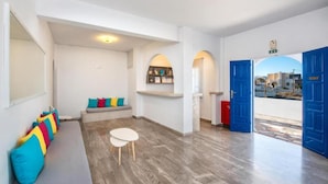 Un interior modern amb zona de seients, una taula petita i vista a través d'una porta oberta.