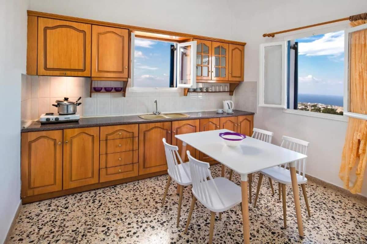 A kitchen with wooden cabinets, a white table, and chairs.