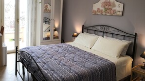 A bedroom with a bed, a wardrobe, a mirror, a nightstand, and a wall-mounted key holder.