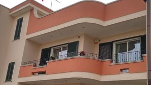 A multi-story building with balconies, windows with shutters, and a curved architectural design.