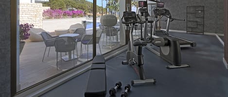 Un gimnasio con equipo de ejercicio, una banca y mancuernas.