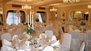 A banquet hall with round tables set for a formal event, featuring white tablecloths, glassware, and floral centerpieces. - The Revelstoke Hotel (Bridlington)