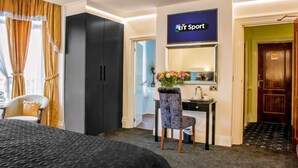 A hotel room with a bed, a desk with a chair, a wardrobe, a mirror, and a sign for BT Sport. - The Revelstoke Hotel (Bridlington)