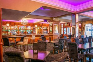 Uma área de bar com mobiliário de madeira, balcão e um candelabro.