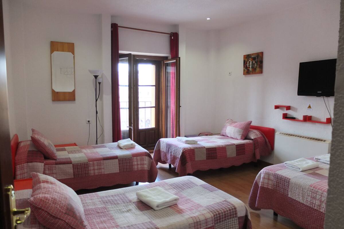 Une chambre d’hôtel avec deux lits, chacun recouvert d’une couvre-lit à carreaux et agrémenté d’oreillers, un téléviseur à écran plat fixé au mur et une petite table avec une chaise.