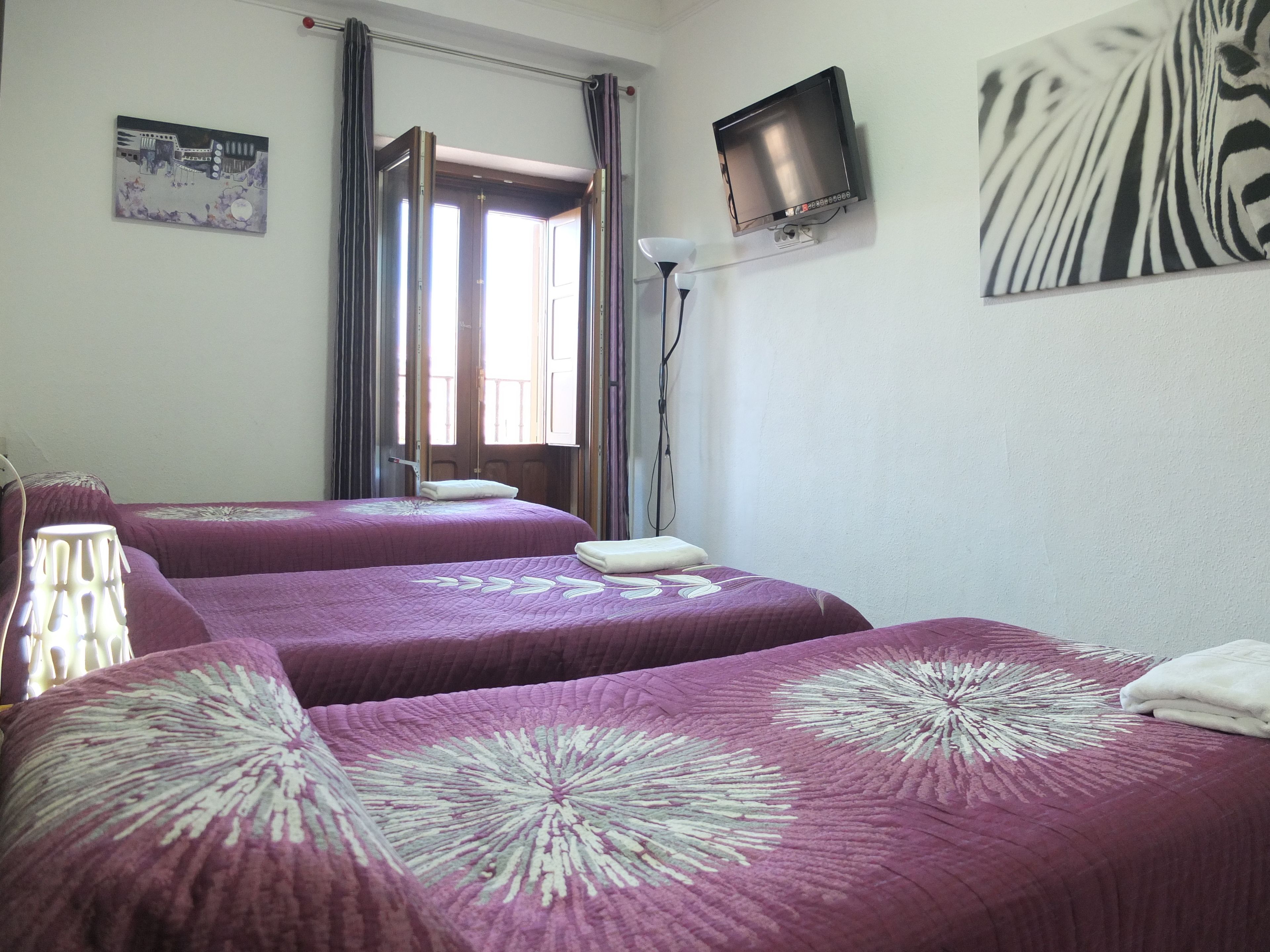 A hotel room with two beds, a television, and a painting on the wall.