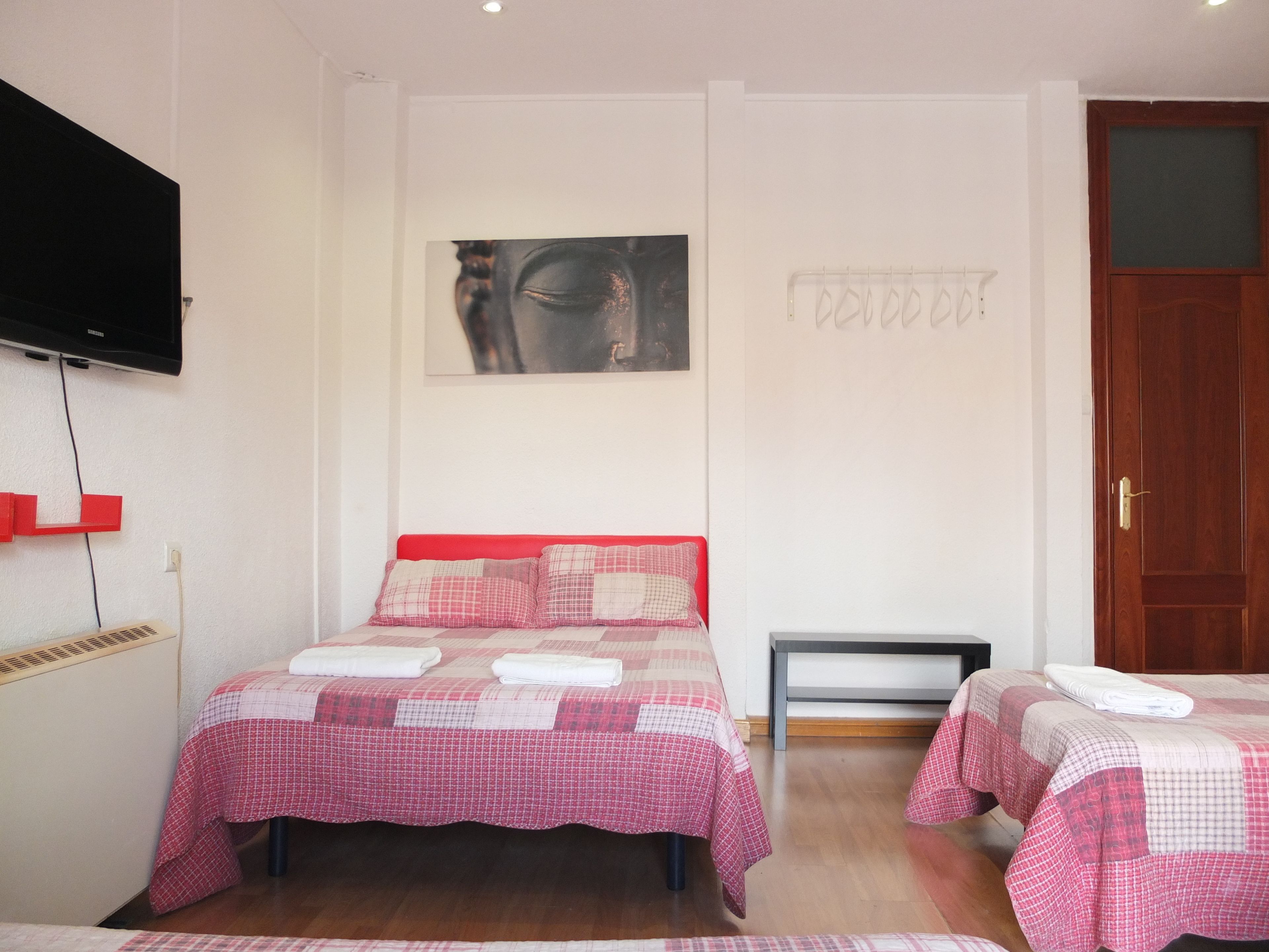 Une chambre d’hôtel avec deux lits, un téléviseur à écran plat fixé au mur et un tableau au-dessus des lits.