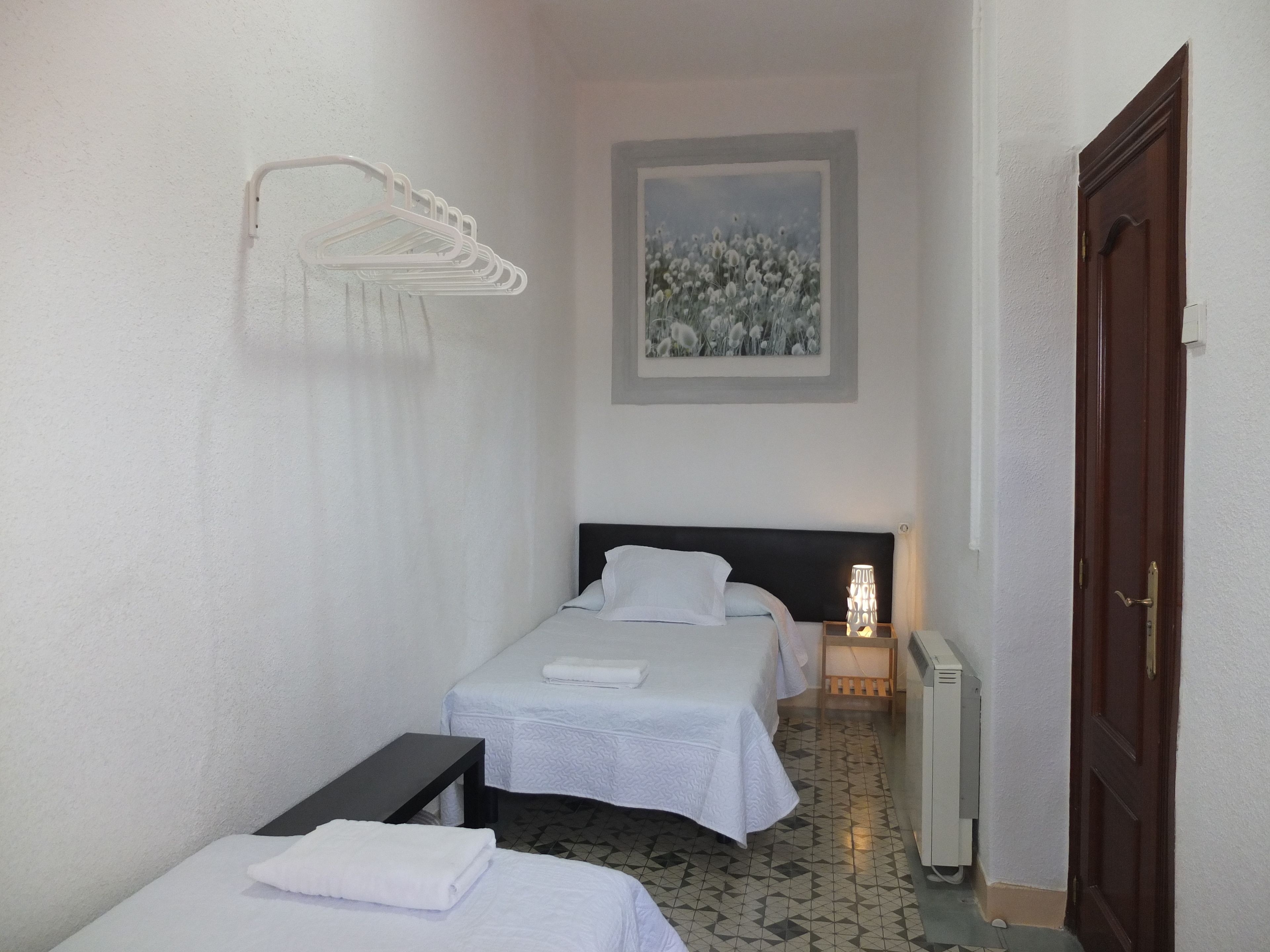 Une chambre d’hôtel avec deux lits, un tableau au mur, un radiateur et une porte.