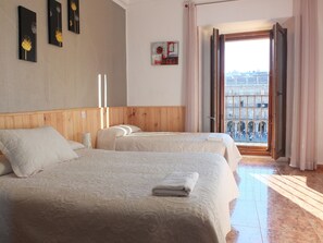 Hotelkamer met twee bedden, een houten hoofdeinde, een raam met uitzicht op de stad en een schilderij aan de muur.