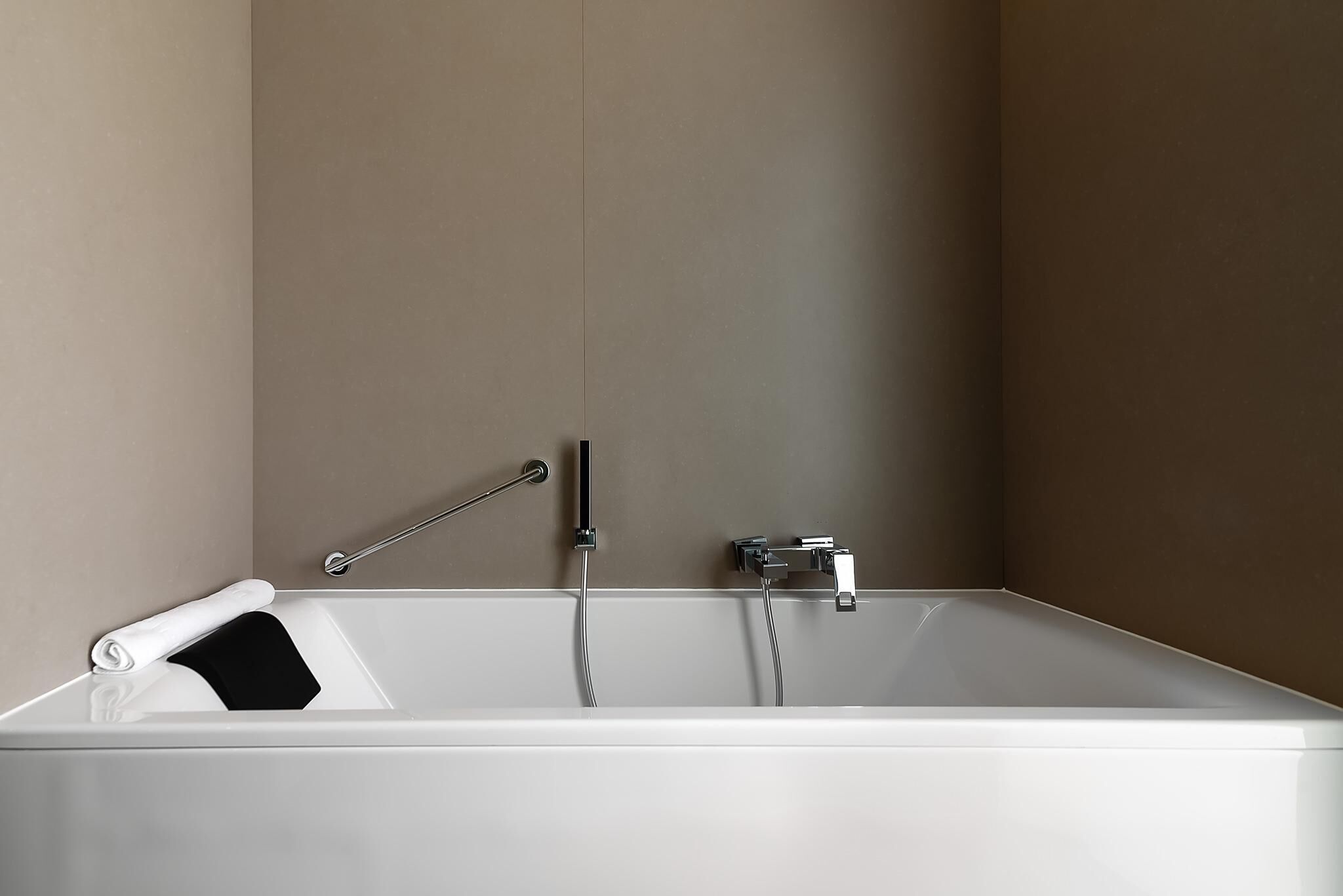 A modern bathroom with a bathtub, a towel, and a shower control.