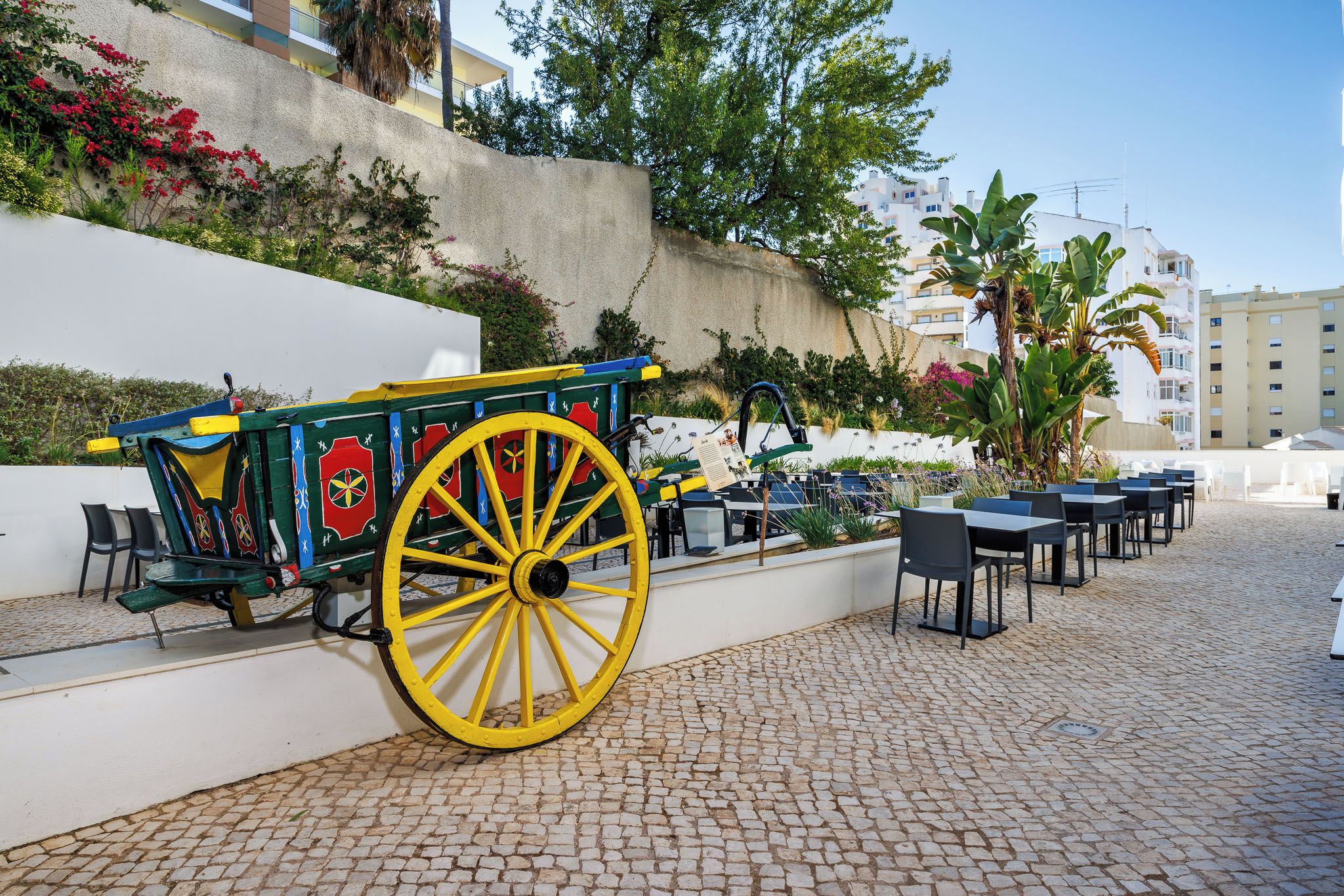 A cobblestone patio with outdoor seating and a colorful carriage.