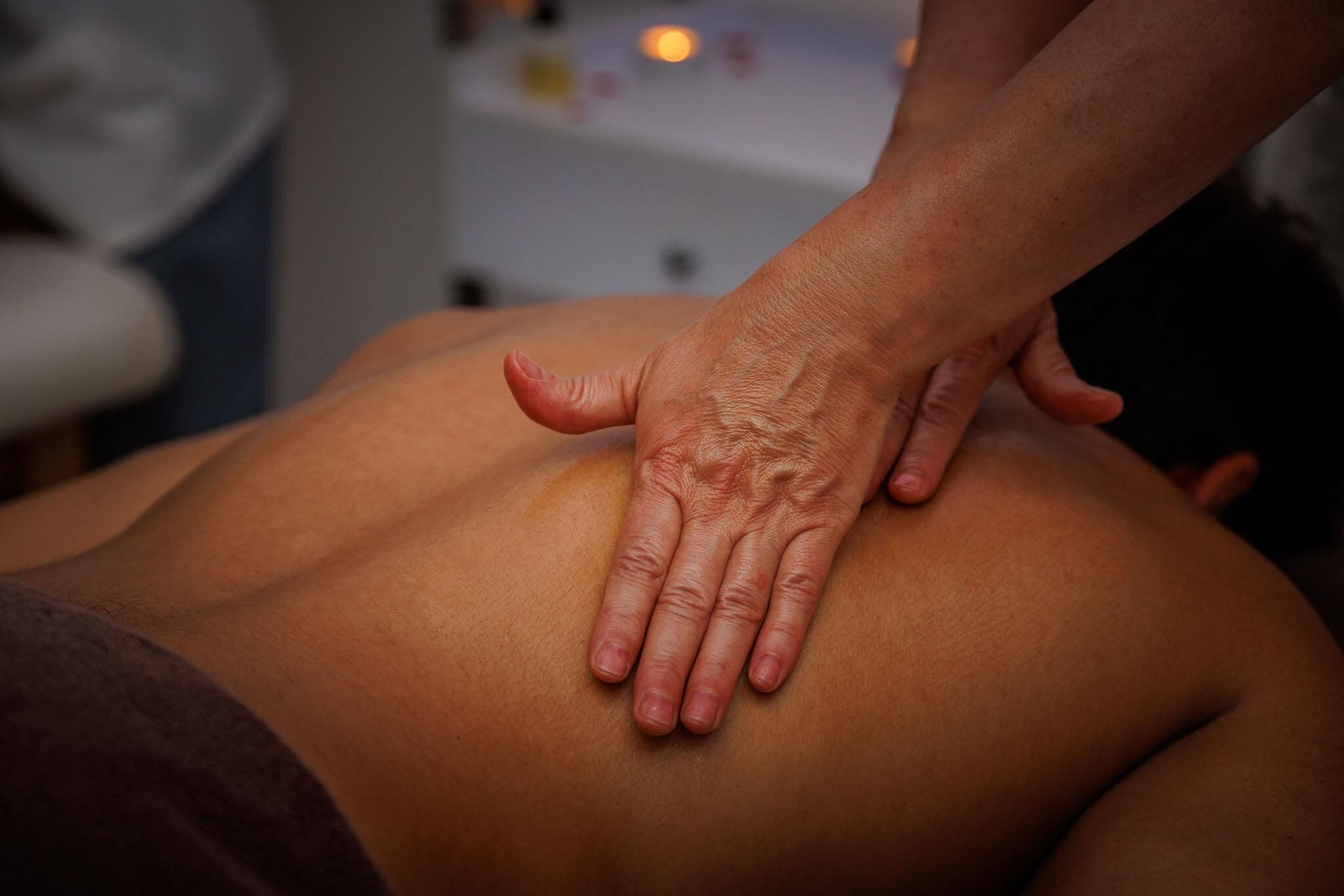 Gros plan d’une main effectuant un massage sur le dos d’une personne.