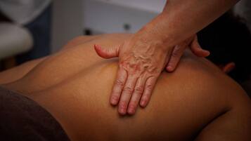 A close-up of a hand performing a massage on a person's back.