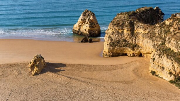 Ein Strand mit Felsformationen und freiem Blick auf das Meer.