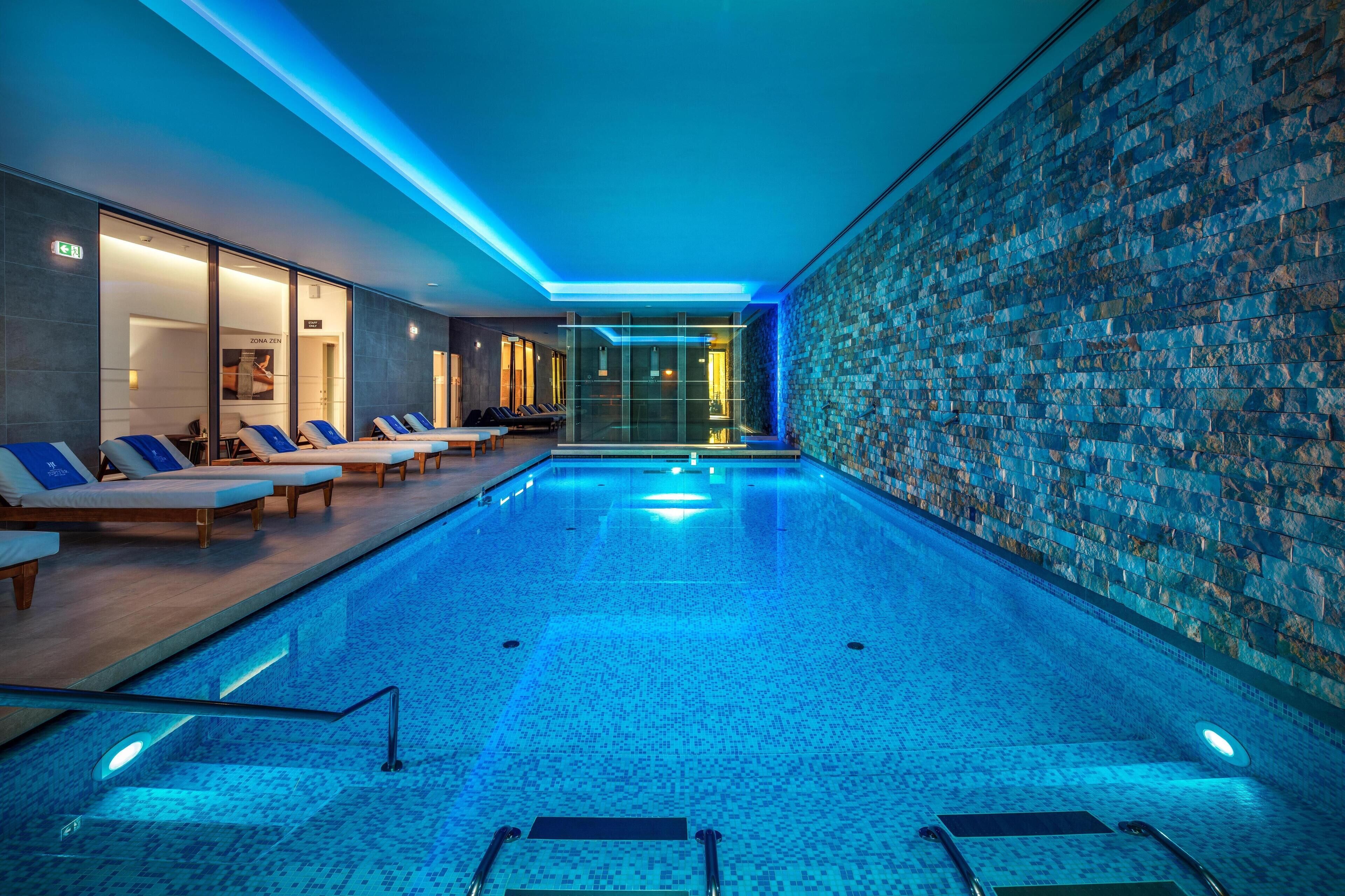 Una piscina cubierta, una piscina al aire libre, sombrillas, tumbonas