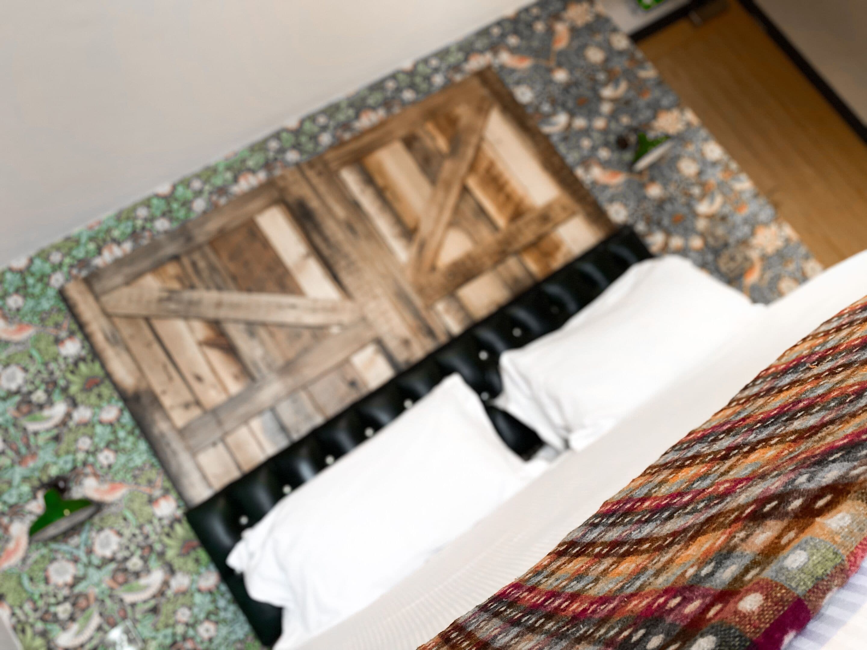 A bed with a patterned bedspread, a wooden headboard, and a white pillow.