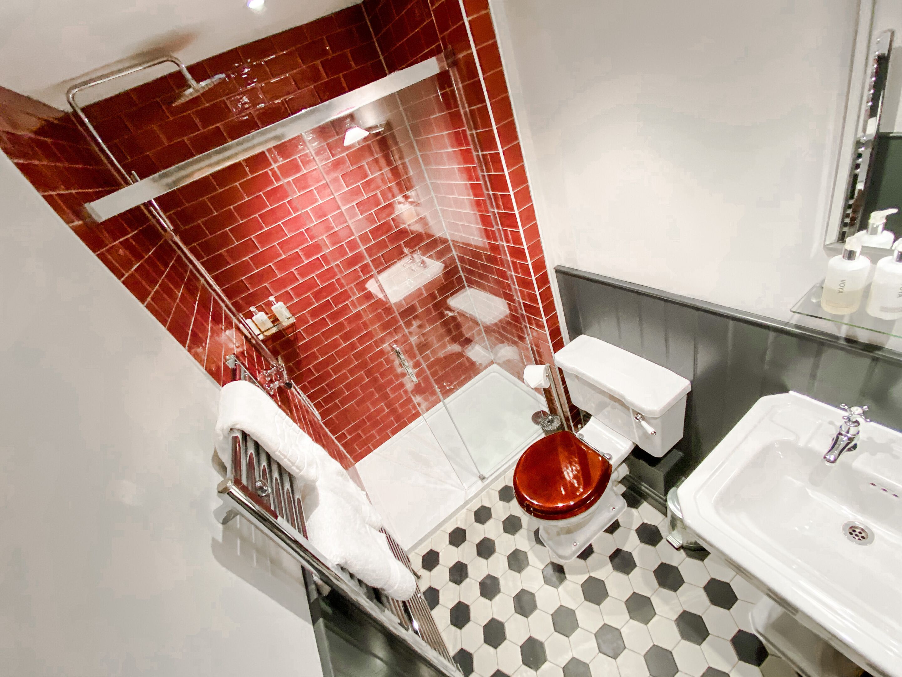 Een moderne badkamer met een douchecabine van glas, een wit toilet en een wastafel met spiegel.