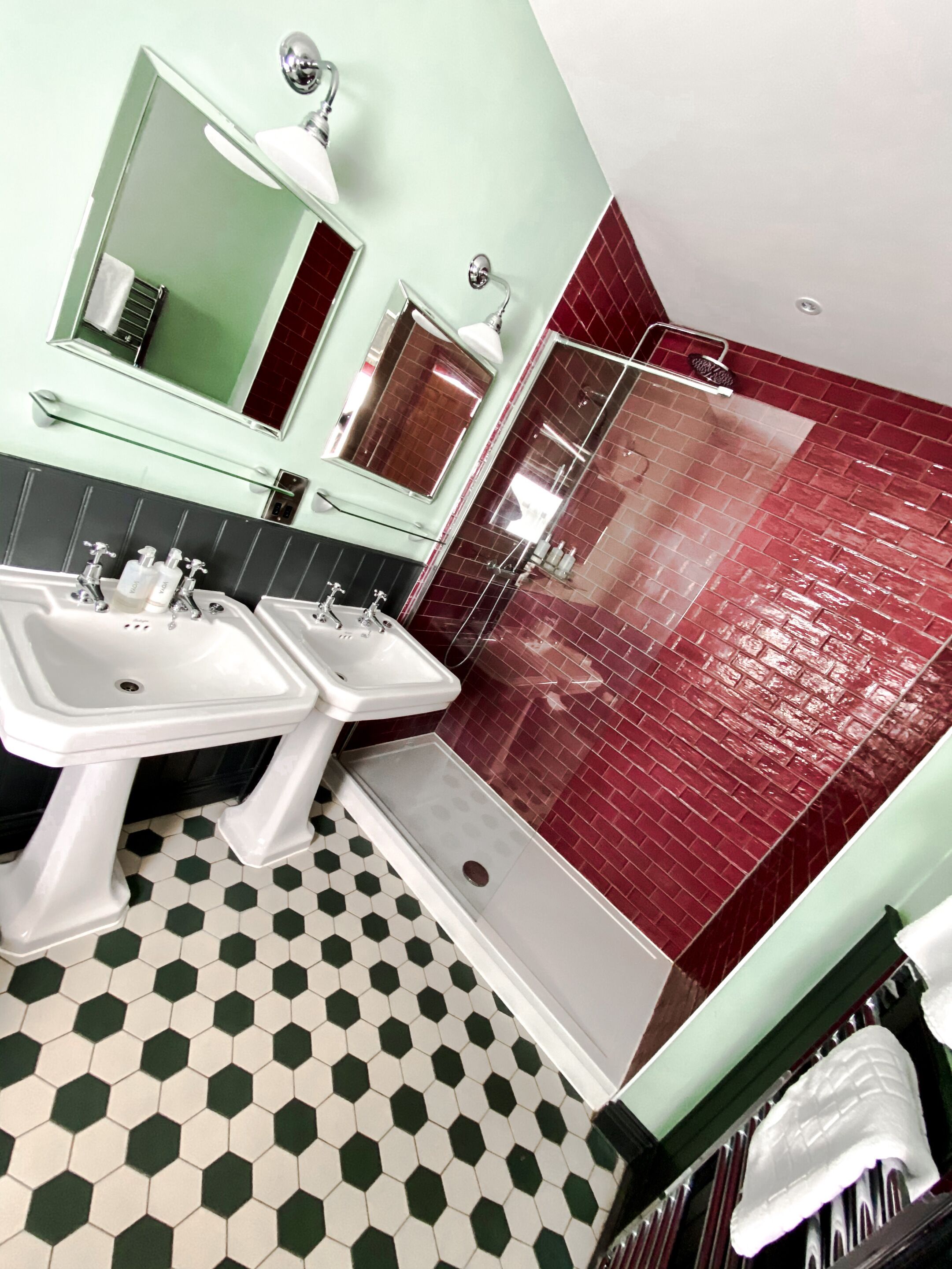 A bathroom with two sinks, a mirror, and a shower area.