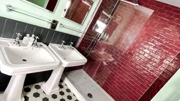 A bathroom with two sinks, a mirror, and a shower area.