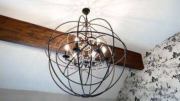 Un lustre au design géométrique, doté de plusieurs ampoules, fixé à une poutre en bois.