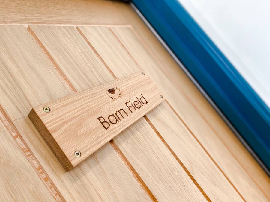 A wooden plaque with the engraving "Barn Field" on a wooden floor.