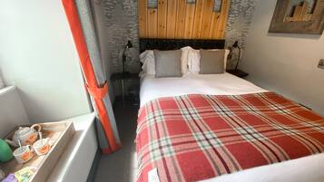 A neatly made bed with a plaid blanket, a wooden headboard, and a small bedside table with a lamp.