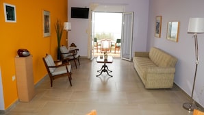 Uma sala de estar com sofá, cadeiras, mesa e televisão.