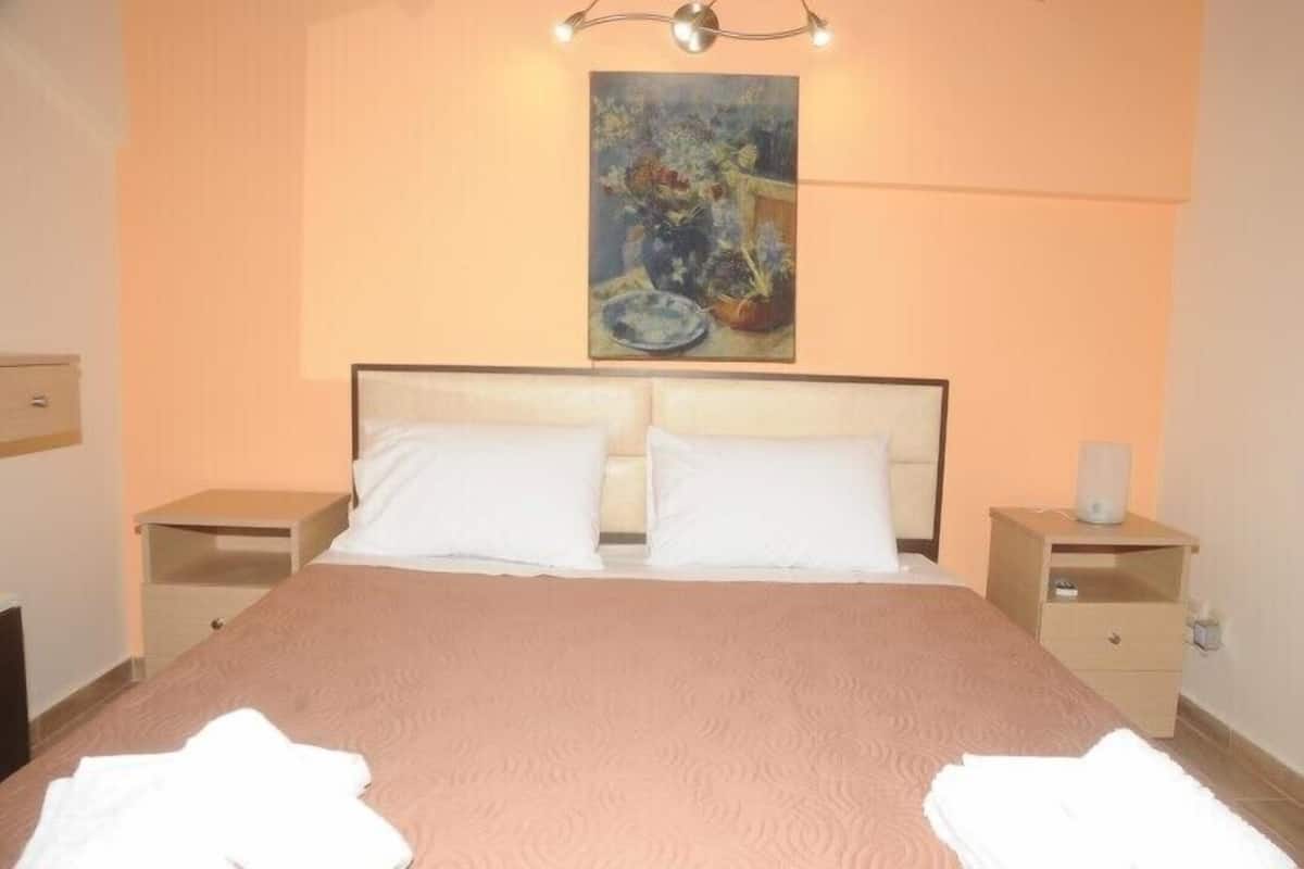 Un lit bien fait, avec du linge de lit blanc, une tête de lit et deux tables de chevet avec des lampes.