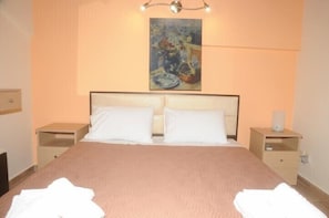 A neatly made bed with white linens, a headboard, and two bedside tables with lamps.