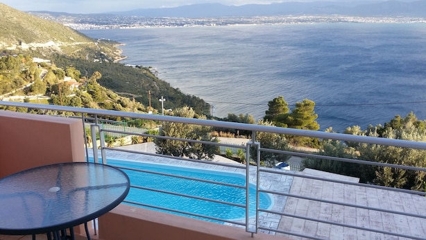 Varanda com mesa de vidro, vista para piscina e para o litoral.