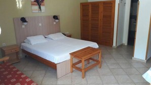 A neatly arranged bedroom with a bed, bedside tables, a wooden bench, and a wardrobe. - Zafiria Apartments (Samos)