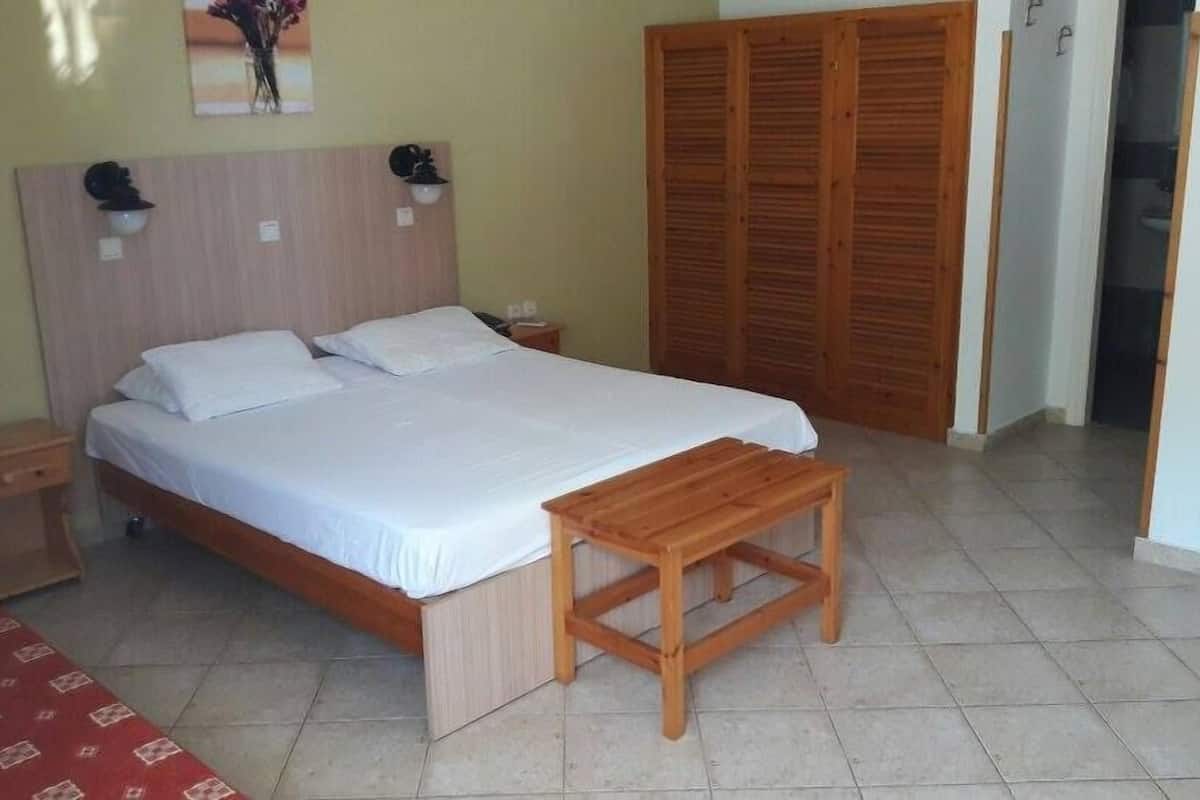 A neatly arranged bedroom with a bed, bedside tables, a wooden bench, and a wardrobe.
