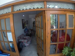A room with a wooden partition, a sofa, a vase with flowers, and a sign on the wall.