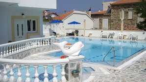 A swimming pool with a decorative dolphin float, stone flooring, and a white balustrade. - Zafiria Apartments (Samos)