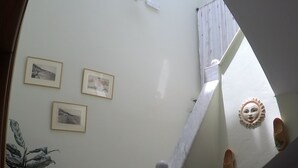 A staircase with white walls, three framed pictures, and a potted plant. - Zafiria Apartments (Samos)