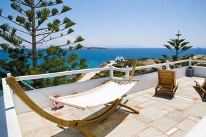A hammock on a terrace with a view of the sea and a white building in the distance. - Martineli Residence (Paros)