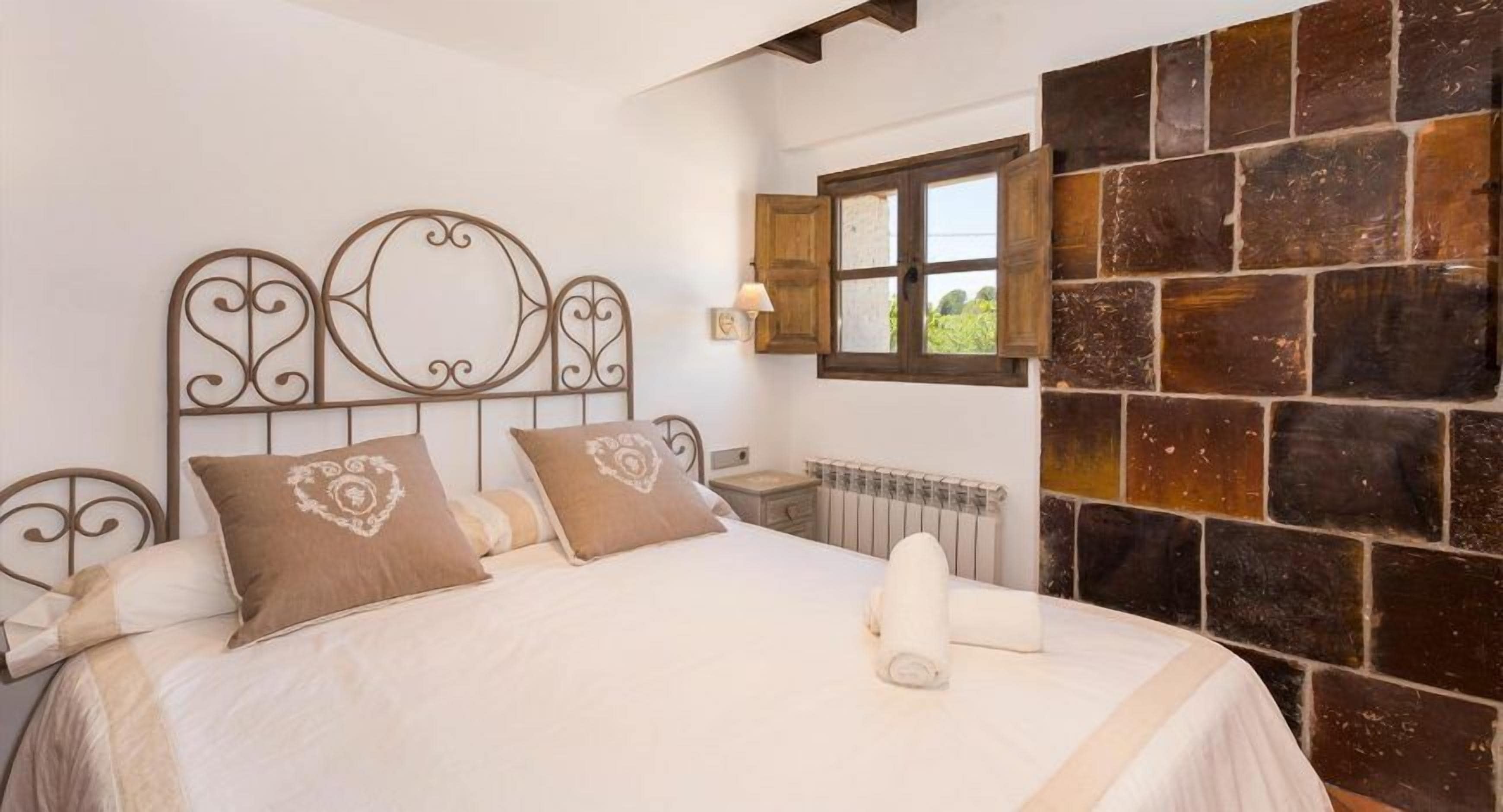Un dormitorio con cama, un radiador, una ventana y una pared de piedra.
