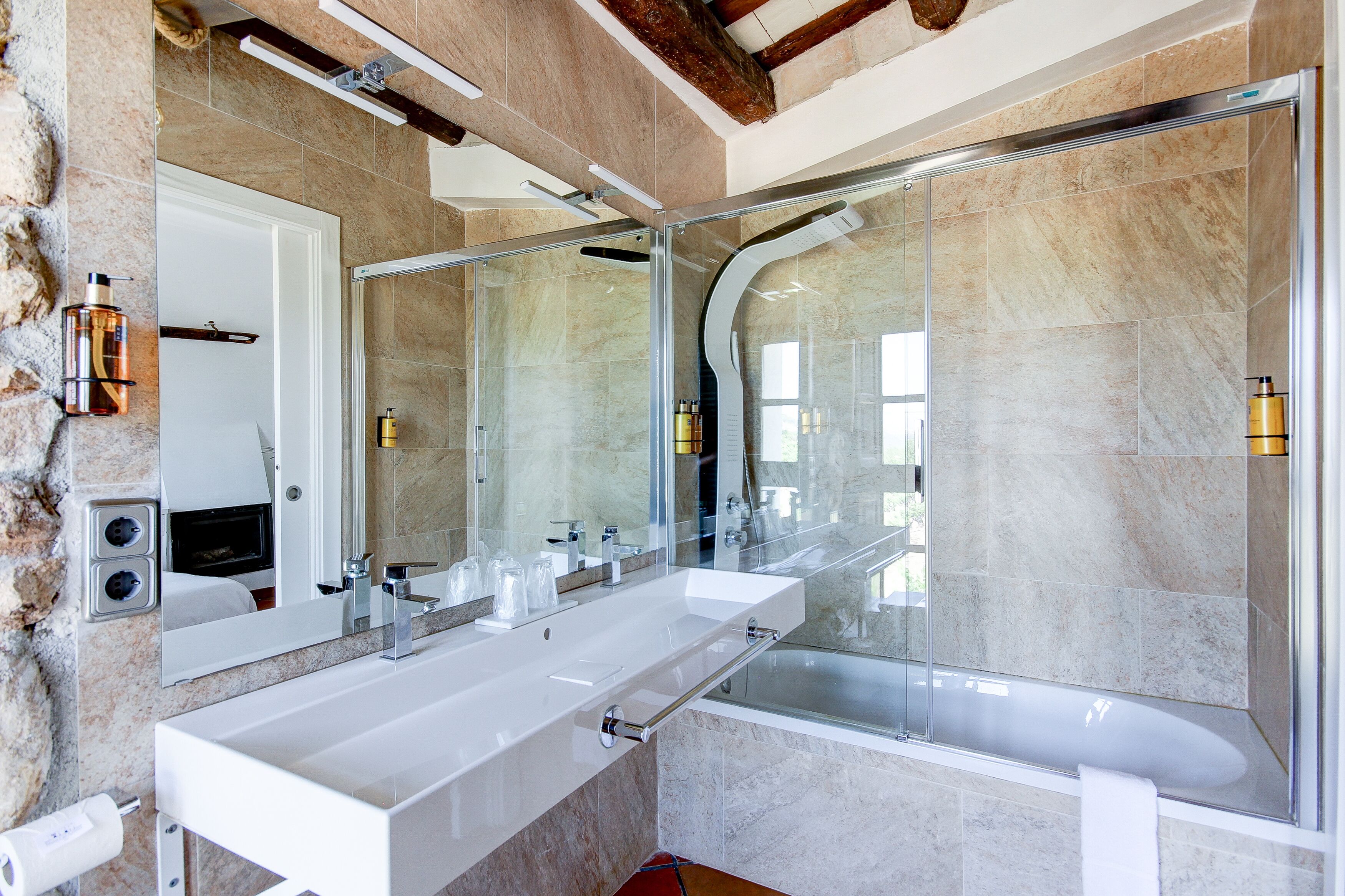 Een moderne badkamer met een grote spiegel, twee wastafels, een bad en een douche met glazen wanden.
