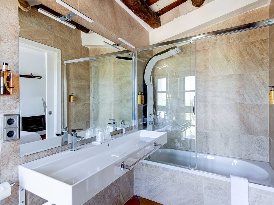 Een moderne badkamer met een grote spiegel, twee wastafels, een bad en een douche met glazen wanden.