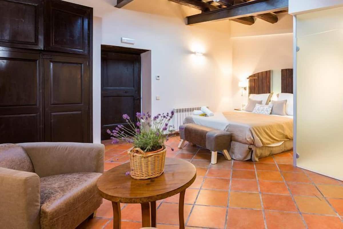 A bedroom with a bed, a sofa, a small table with a basket, and a wardrobe.