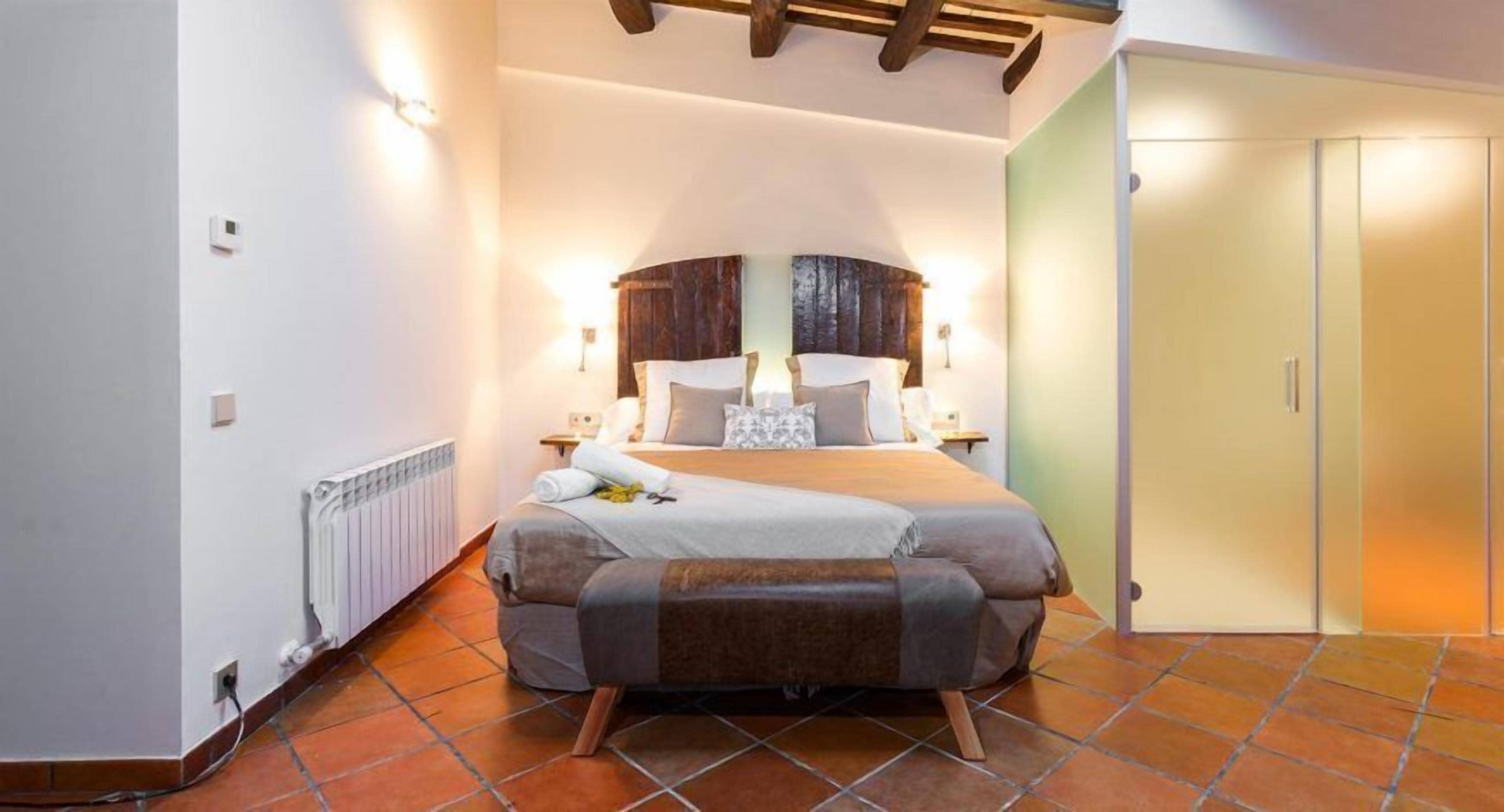 Un dormitorio con cama, radiador, techo de madera y puerta.