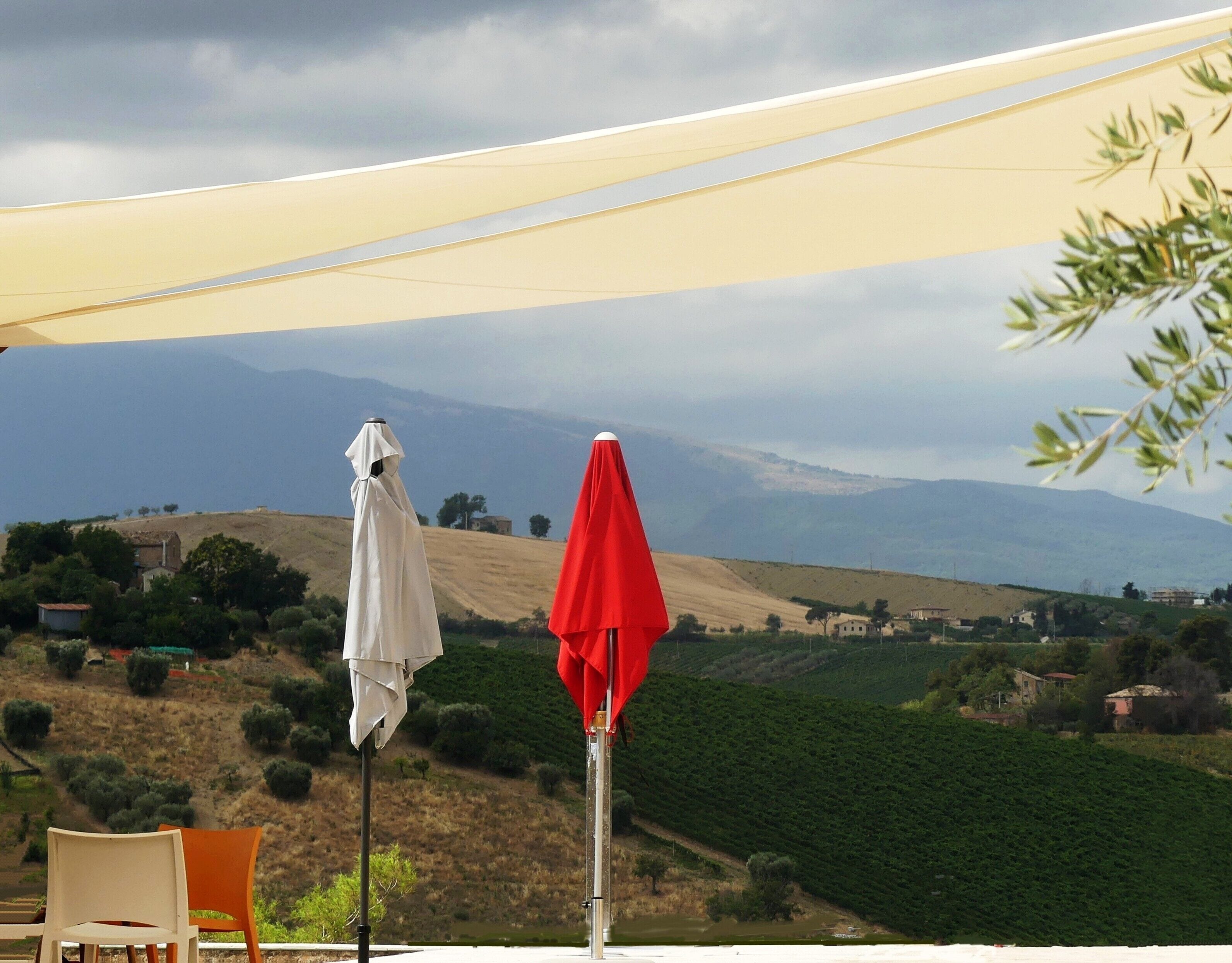 A terrace with two chairs and a table, overlooking a vineyard and distant hills.