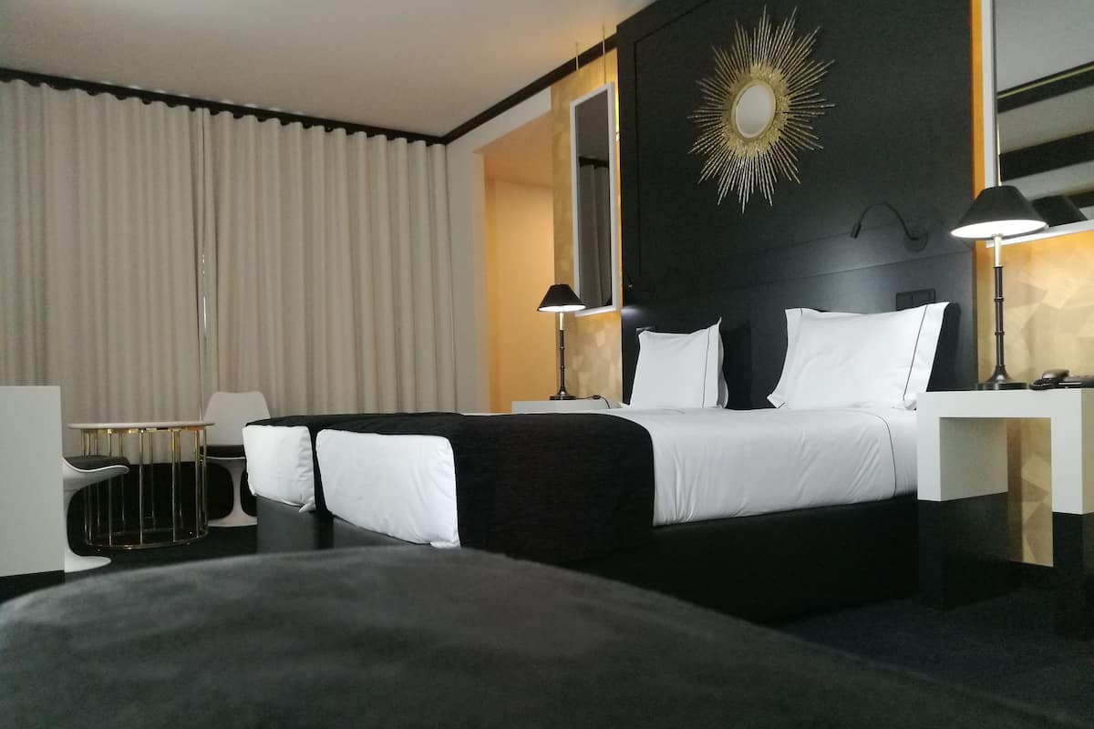 A hotel room with a large bed, two bedside tables, a desk, and a chair.