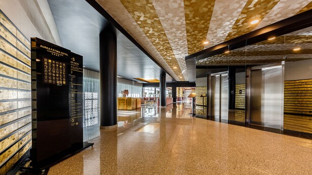 A hotel corridor with a polished floor, a directory on the left, and elevators on the right. - Aurea Fátima Hotel Congress & Spa (Ourem)