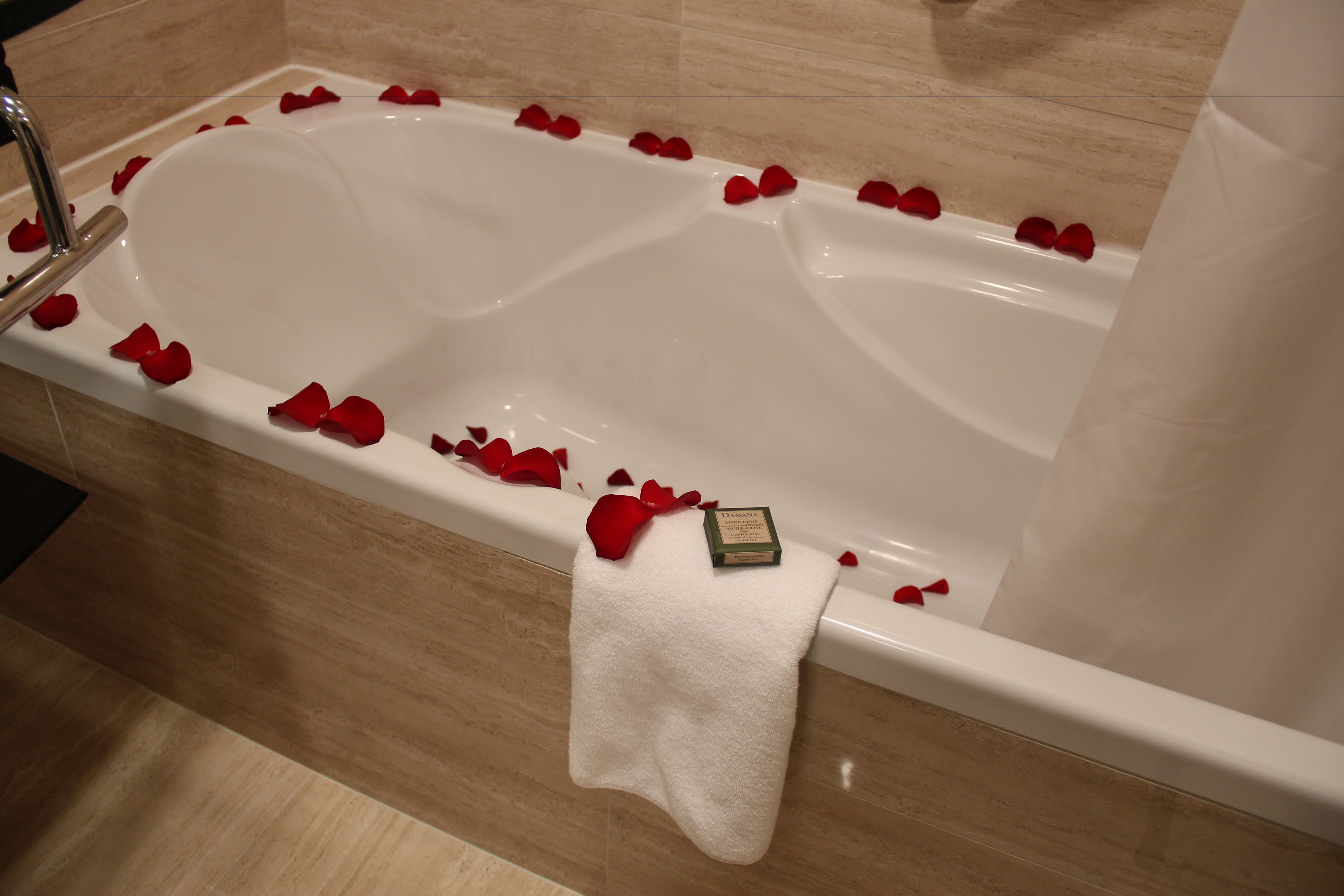 A bathtub with rose petals and a towel.