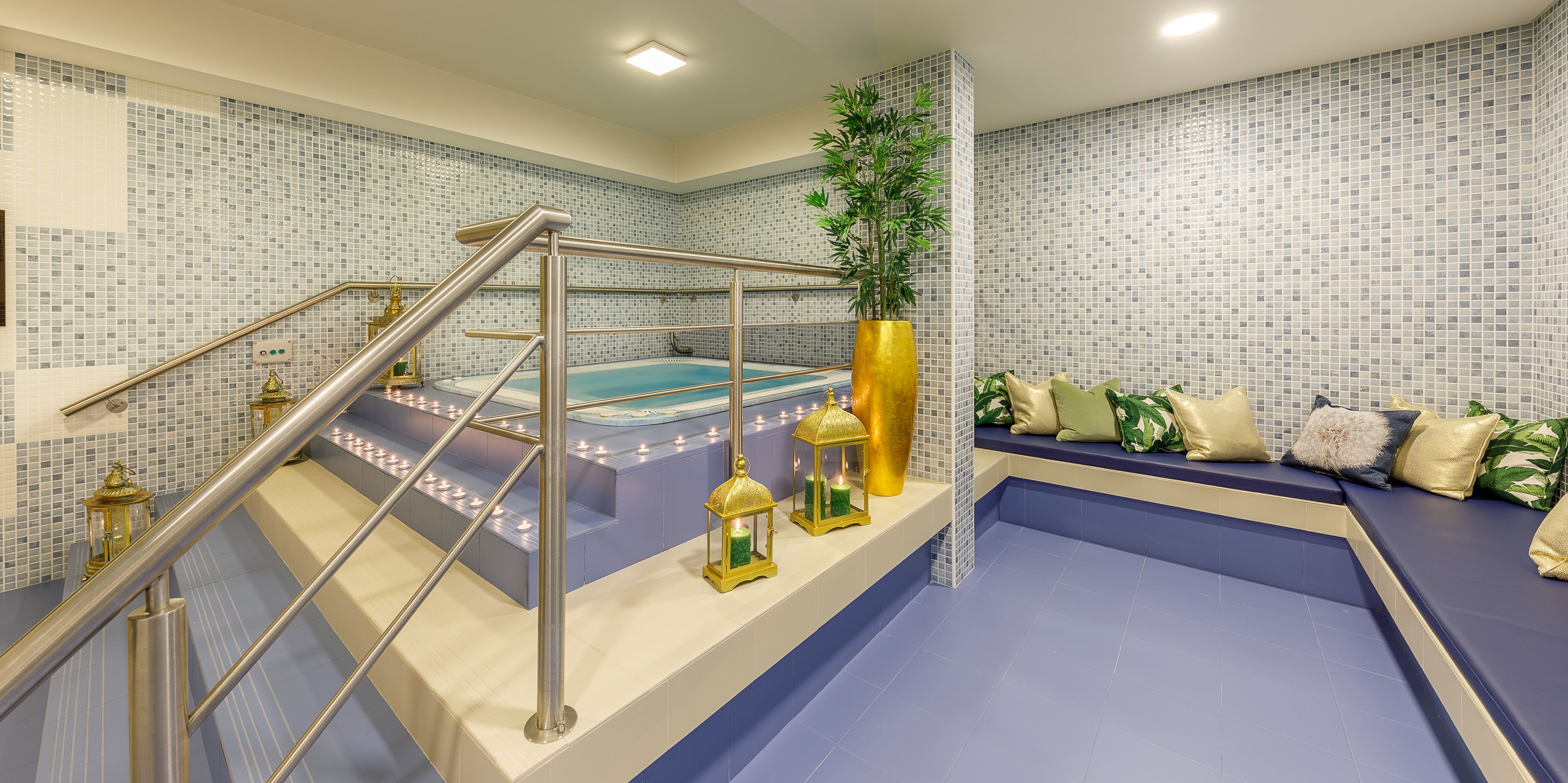 A spa area with a hot tub, a staircase with metal railings, and a seating area with cushions.