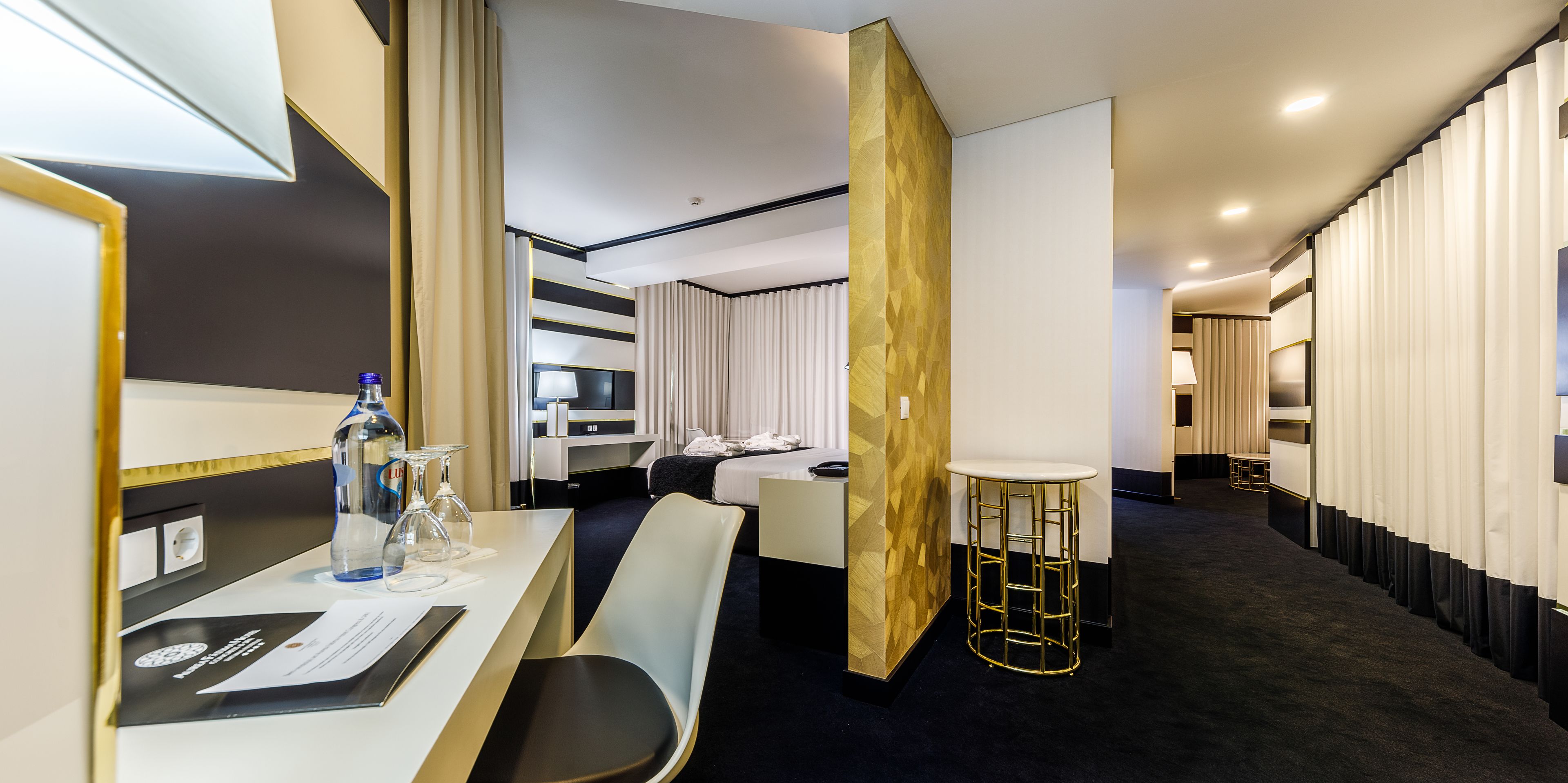 A hotel room with a bed, bedside table, and a seating area with a chair and a small round table.