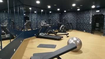 Un gimnasio con equipo de ejercicio, un espejo grande y una pelota de ejercicio de gran tamaño.