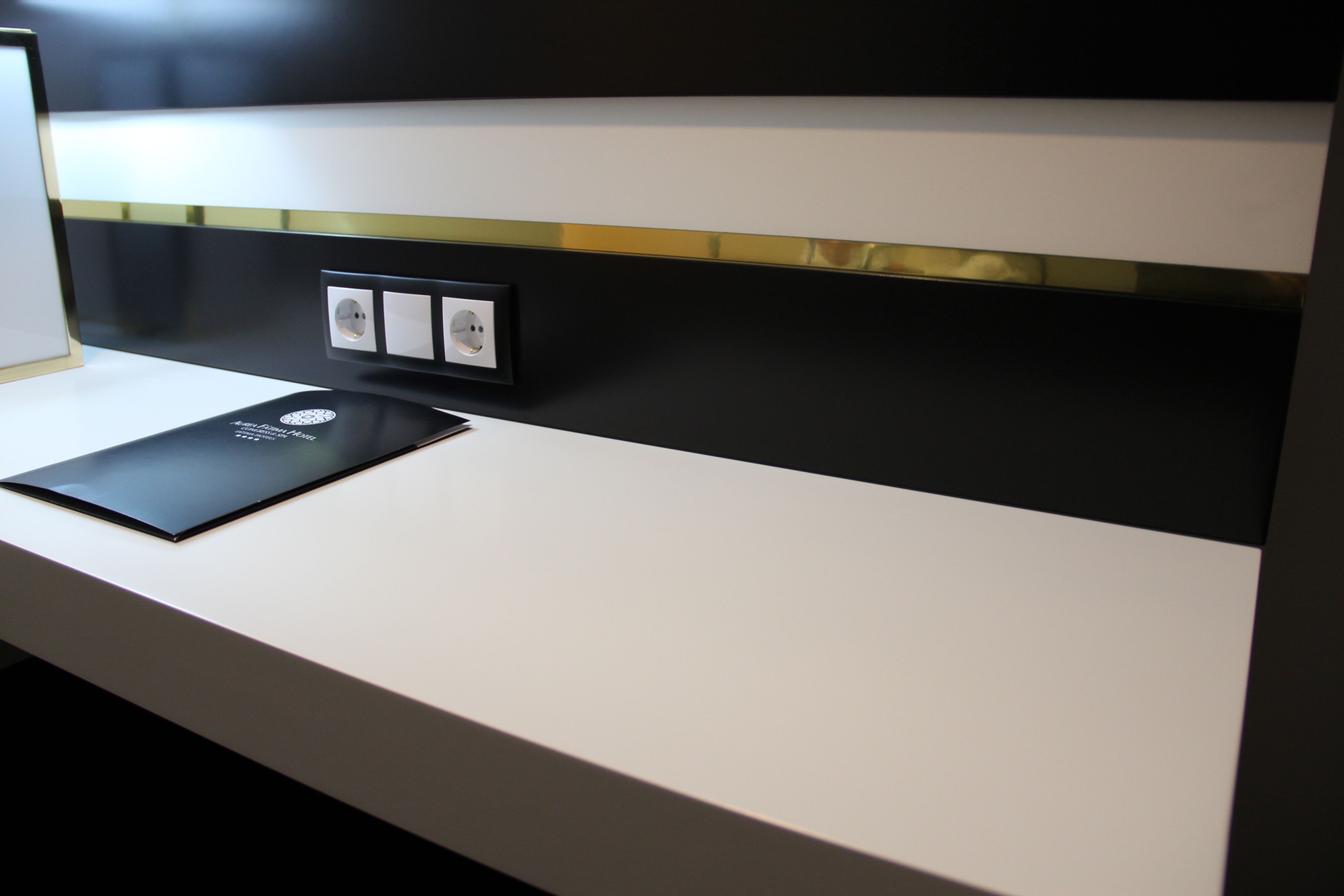 A modern hotel reception desk with a flat-screen TV, a black tablet, and a power outlet.